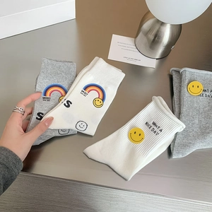 Detail view of cotton crew socks featuring rainbow embroidery and smiley face patches