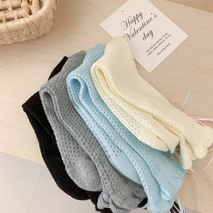 Détail de quatre paires de chaussettes en tricot ajouré gris, bleu, noir et beige en coton