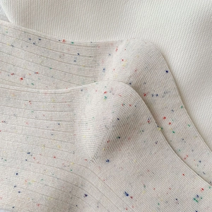 Close-up of cream ribbed knit socks with colorful speckled yarn detail and soft texture