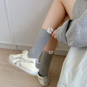 Détail de chaussettes en tricot gris avec étiquette cœur et baskets rétro