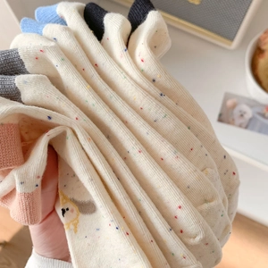 Close-up of soft cotton socks with colorful speckled patterns and cute puppy embroidery