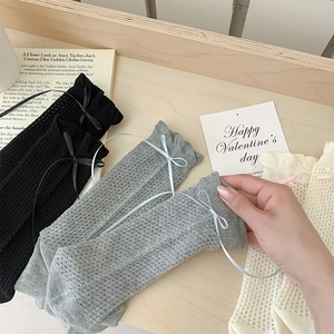 Gros plan de chaussettes en maille ajourée avec nœuds en noir, gris et beige