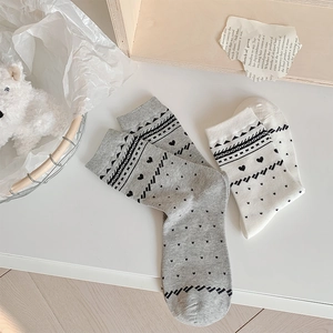 Detail of grey and white mid-calf socks with heart patterns in a cozy home setting