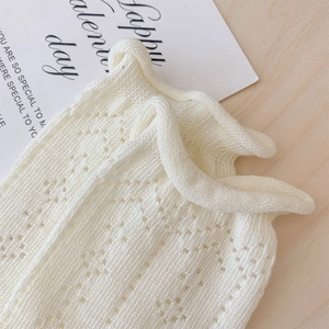 Close-up of white mesh hollow knit pattern on socks with festive gift card background