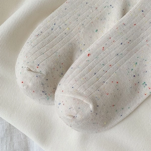 Detail of off-white vertical ribbed socks with colorful knit dots and soft cotton texture