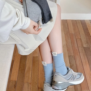 Détail de chaussettes en coton côtelé avec étiquettes logo cœur en bleu et gris