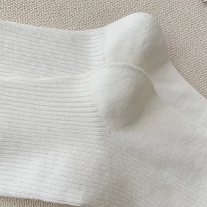 Vue détaillée de la maille côtelée blanche montrant la texture verticale fine et le tissage
