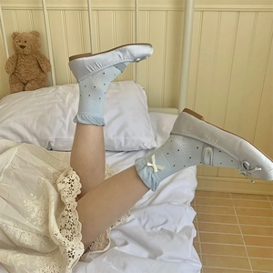 Dettaglio di scarpe Mary Jane argento con fiocco e calze a pois blu con volant eleganti