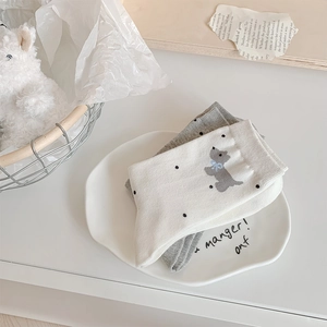 Detail of cotton crew socks featuring polka dots and cute puppy embroidery in a cozy setting