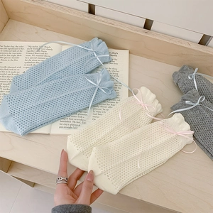 Détail de nœuds en ruban et texture de maille ajourée sur chaussettes mi-hautes femme