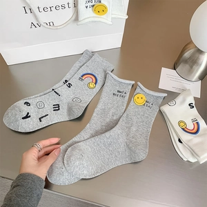 Detail of knitted cotton socks featuring smiley face, rainbow prints and letter embroidery
