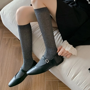 Detail of dark grey shimmering knee-high socks with silver glitter and black Mary Jane shoes
