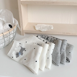 Detail of neatly folded cotton socks featuring cute puppy and bow patterns in white and grey