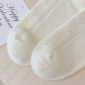 Detail of cream knit socks featuring delicate hollow floral patterns and soft texture