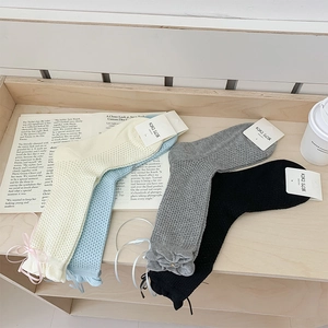 Détail de chaussettes en maille ajourée avec rubans en ivoire, bleu, gris et noir