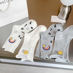 Close-up of ribbed cotton socks with embroidered rainbow and yellow smiley face details