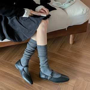 Close-up of ballet-style gray glitter socks paired with black Mary Jane flat shoes