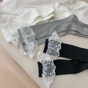 Détail de la bordure en dentelle et de la maille côtelée sur chaussettes ivoire, grises et noires