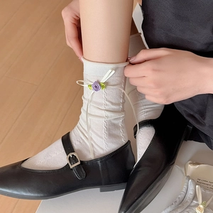 Detail of white knit socks featuring purple satin roses and bow with Mary Jane shoes
