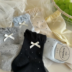 Dettaglio di polsini a balze e fiocchi su calze a pois in vari colori pastello eleganti