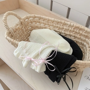 Détail de chaussettes en maille ajourée avec nœuds en ruban dans un panier