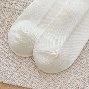 Macro shot of white ribbed knit cotton socks showing the detailed vertical striped texture