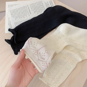 Close-up of knit mesh hollow socks in black and beige with wavy curled edges