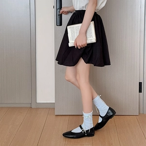 Detail of light blue bow socks paired with black Mary Jane shoes and a pleated skirt