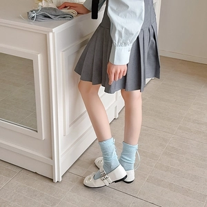 Détail de chaussettes résille bleu clair avec nœuds et chaussures Mary Jane blanches