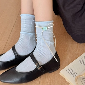 Close-up of light blue knit socks with 3D floral and white ribbon bow details