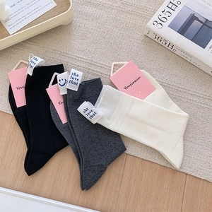 Close-up of ribbed cotton crew socks in black, grey, and off-white with smiley face labels