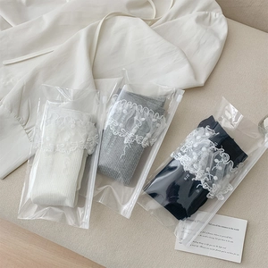 Détail de chaussettes en coton tricolores avec bordure en dentelle brodée en emballage