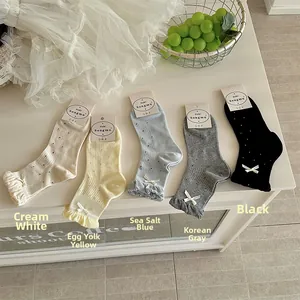 Dettaglio di cinque calze a pois con volant e fiocchi in crema, giallo, blu, grigio e nero