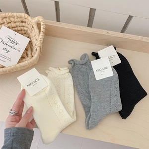 Close-up of sweet mesh hollow knit socks with wave edges in beige, gray and black colors