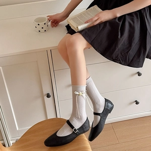 Detail of grey knitted socks with white bows and 3D yellow flowers paired with Mary Janes