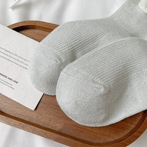 Detail shot of silver glitter ribbed calf socks with metallic yarn on a wooden tray