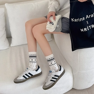 Close-up of cream crew socks with black geometric patterns and cute heart details