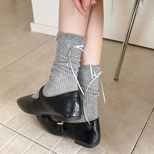Détail de chaussettes en maille grise avec nœud en ruban bleu clair et souliers Mary Jane