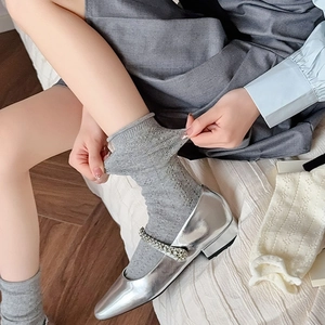 Detailed view of grey mesh hollow knit socks paired with silver glitter Mary Jane shoes