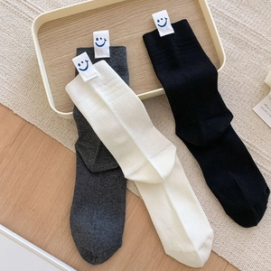 Detailed view of striped cotton crew socks with smiley patch in grey, white, and black sets