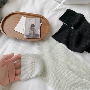 Detailed knit texture of light green and black ballet-style leg warmers on a white cloth