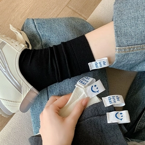 Close-up of knit cotton socks with blue smile label and she love that letter tag