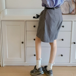 Detail of gray high-waisted tailored shorts with smooth fabric and black slim belt