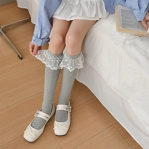 Détail de chaussettes grises côtelées avec dentelle en tulle blanc et broderie à pois