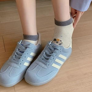 Top view of blue suede sneakers with white stripes and cute cartoon ankle socks
