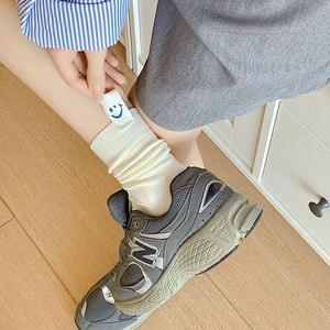 Minimalist cream knit ribbed crew socks featuring a cute blue smiley face patch accent