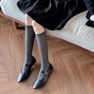 Detailed texture of dark grey glitter calf socks with vertical ribbing and Mary Jane shoes