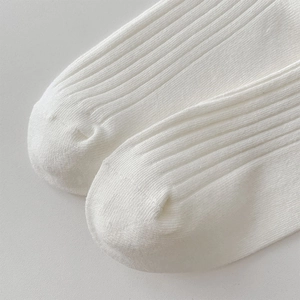 Detailed close-up of white ribbed crew socks with reinforced stitching on the toe area
