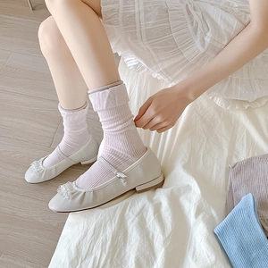 Detail of lavender ribbed knit socks with rolled edge and Mary Jane shoes decoration