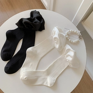 Detail of ruffled lace cuffs on ribbed knit crew socks in black and cream white